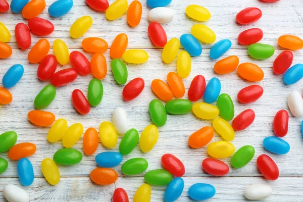 Colorful jelly beans on white wooden background, flat lay