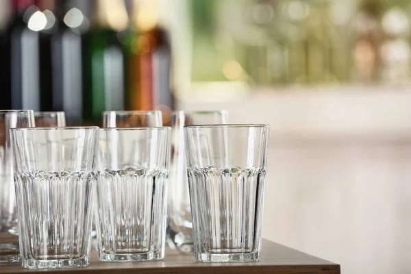 Lege glazen op houten tafel tegen wazige achtergrond — Stockfoto