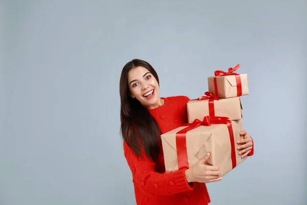 Счастливая молодая женщина с рождественскими подарками на сером фоне. Пространство для текста — стоковое фото