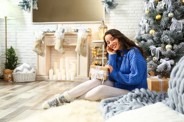 Evde Noel ağacının yanında hediye kutusu olan güzel genç bir kadın. — Stok fotoğraf