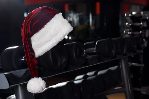 Santa kapelusz na stoisku z hantlami w nowoczesnej siłowni — Zdjęcie stockowe