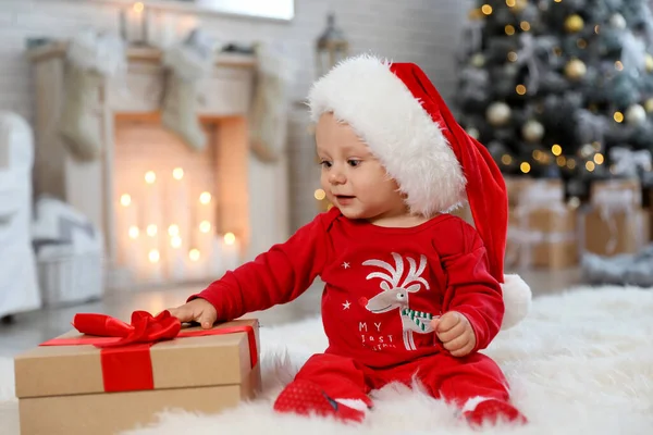 Piccolo bambino con cappello Babbo Natale e regalo di Natale sul pavimento a casa — Foto Stock