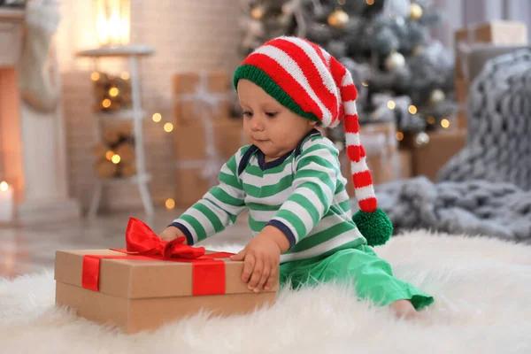 Piccolo bambino con cappello elfo e regalo di Natale sul pavimento a casa — Foto Stock