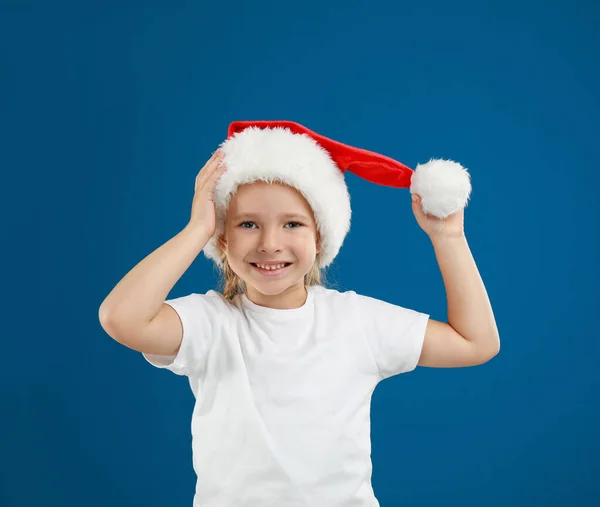 可爱的小孩戴着蓝色背景的圣诞老人帽. 圣诞假期 — 图库照片