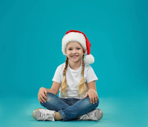 Мила маленька дитина в капелюсі Санта на синьому фоні. Різдвяні свята — стокове фото