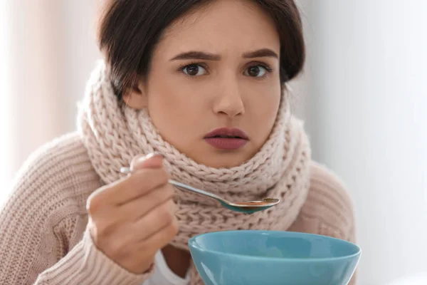 Больная молодая женщина ест суп, чтобы вылечить грипп — стоковое фото
