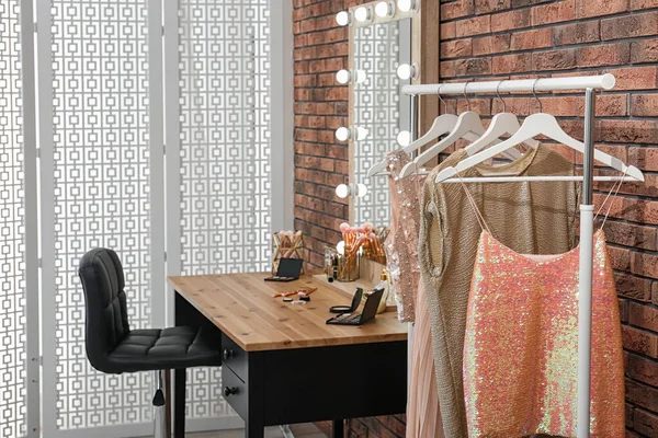 Perchas con ropa elegante en rack en la sala de maquillaje — Foto de Stock