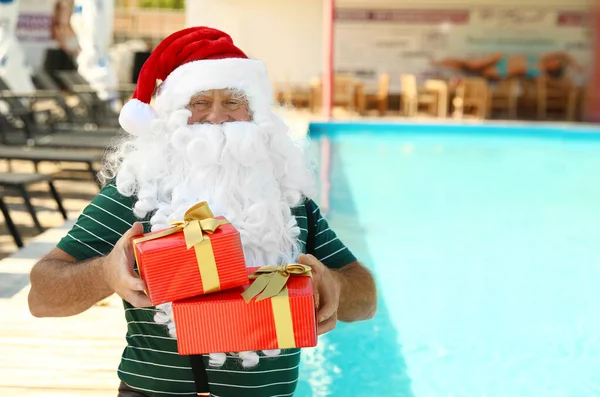 Otelde havuz başında hediye kutuları olan otantik Noel Baba. — Stok fotoğraf