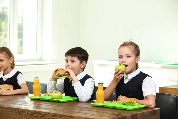 Crianças felizes comendo comida saudável para o almoço na cantina da escola — Fotografia de Stock