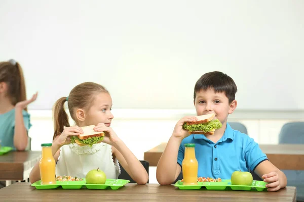 Glückliche Kinder essen gesundes Essen zum Mittagessen in der Schulkantine — Stockfoto