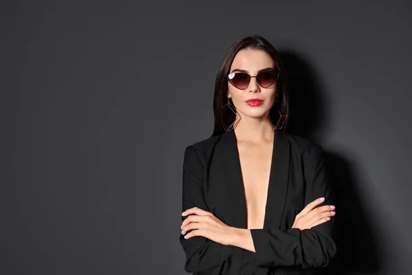 Vacker kvinna bär jacka och solglasögon på svart bakgrund, utrymme för text — Stockfoto