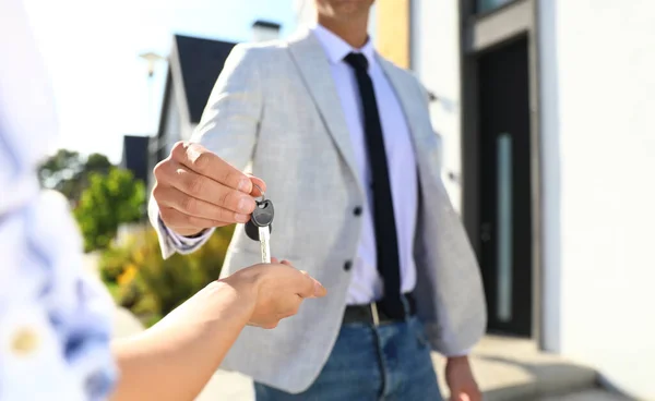 Agent immobilier donnant des clés de maison à la jeune femme à l'extérieur, gros plan — Photo