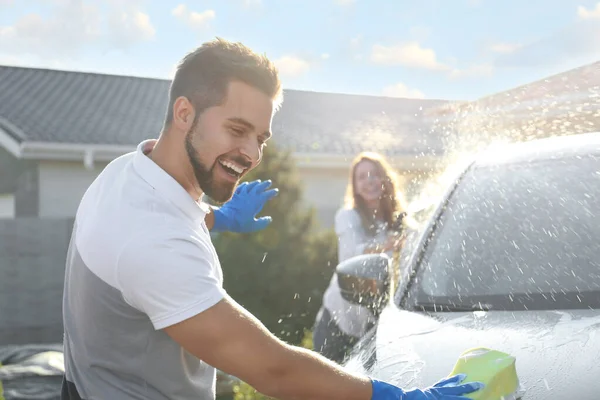 Šťastný pár mytí auta a baví na dvorku na slunný den — Stock fotografie