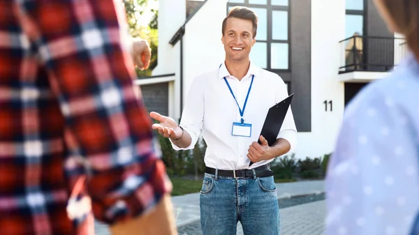 Inmobiliaria mostrando casa a pareja joven al aire libre — Foto de Stock