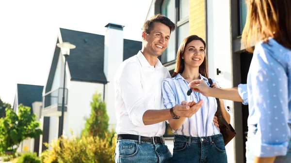 Immobilienmakler übergibt Hausschlüssel an junges Paar — Stockfoto