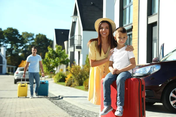 Boldog család bőröndökkel a ház közelében. Költözés napja — Stock Fotó