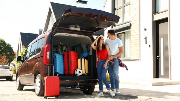 Coppia giovane vicino auto con valigie nel bagagliaio all'aperto. Giorno del trasloco — Foto Stock