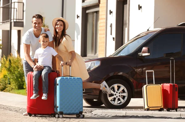 Счастливая семья с чемоданами рядом с домом на улице. День переезда — стоковое фото