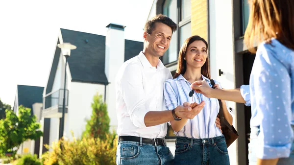 Real estate agent giving house keys to young couple outdoors Royalty Free Stock Images