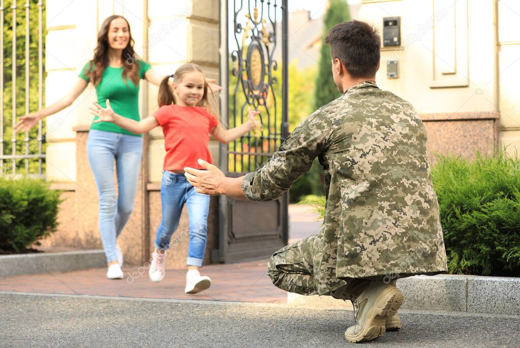Happy family running to man in military uniform outdoors