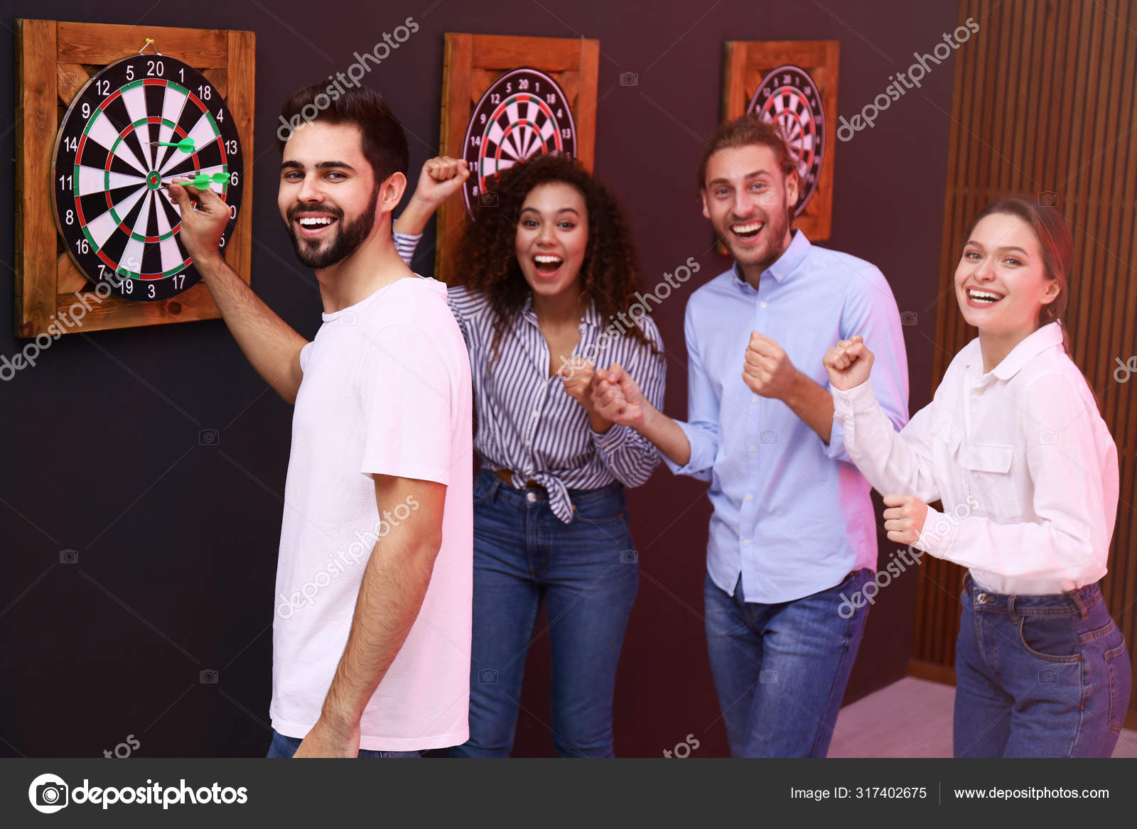 Group of friends playing darts in bar Stock Photo by NewAfrica