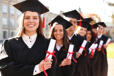 Açık havada diplomalı mutlu öğrenciler. Mezuniyet töreni