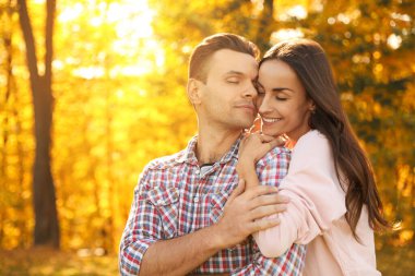 Güneşli parkta mutlu bir çift. Sonbahar yürüyüşü