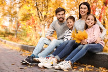 Çocuklu mutlu bir aile parkta vakit geçiriyor. Sonbahar yürüyüşü