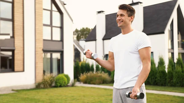 Hombre deportivo haciendo ejercicio con pesas en el patio trasero. Estilo de vida saludable — Foto de Stock