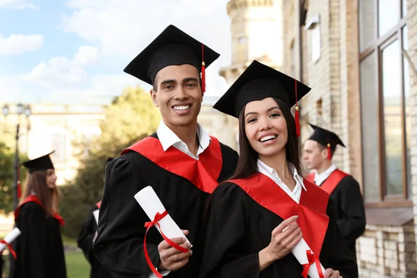 Estudiantes felices con diplomas al aire libre. Ceremonia de graduación — Foto de Stock