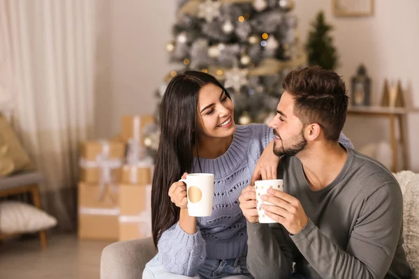Joyeux couple avec boissons dans le salon décoré pour Noël — Photo