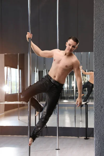 Attractive young man dancing in studio with poles — Stockfoto