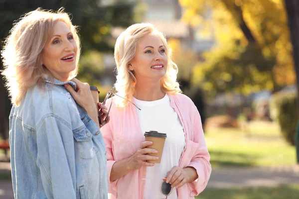 Щасливі зрілі жінки з кавою в парку в сонячний день — стокове фото