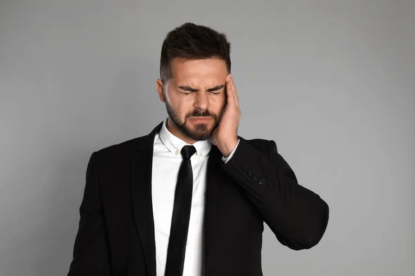 Businessman suffering from headache on light grey background — Stock Photo, Image