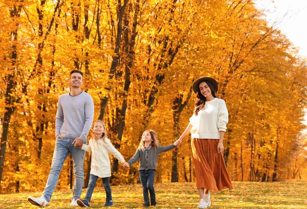 Familia feliz con pequeñas hijas caminando en el parque de otoño — Foto de Stock