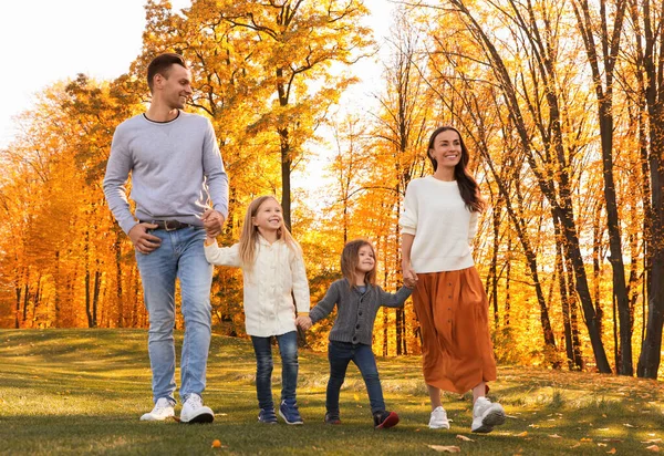 Familia feliz con pequeñas hijas caminando en el parque de otoño — Foto de Stock