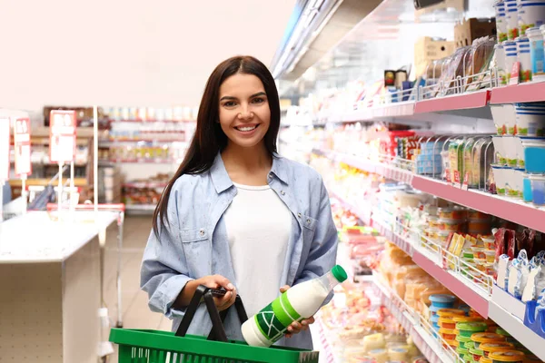 Молодая женщина с корзиной в супермаркете — стоковое фото