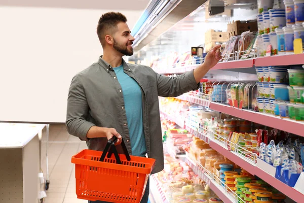 Jovem com cesta de compras no supermercado — Fotografia de Stock