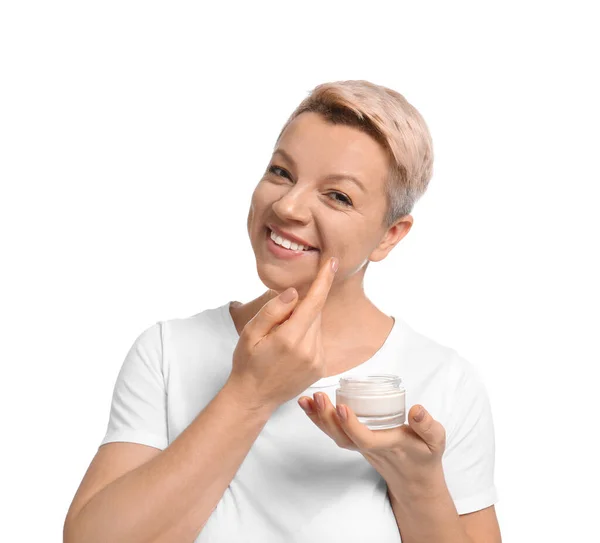 Mujer madura aplicando crema facial sobre fondo blanco —  Fotos de Stock
