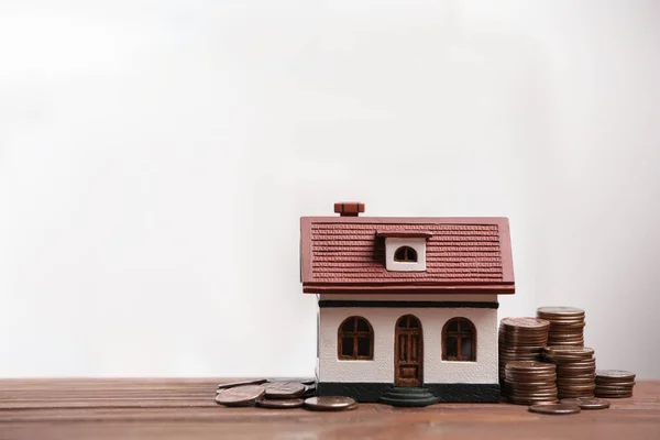 Modelo de casa y monedas sobre mesa de madera, espacio para texto. Ahorro de dinero —  Fotos de Stock