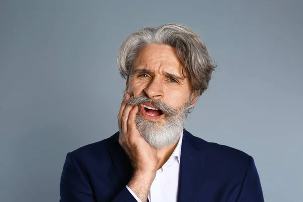 Man suffering from toothache on grey background — Stock Photo, Image