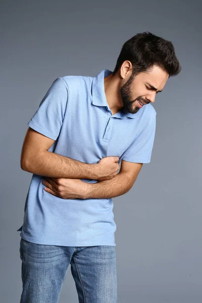 Man suffering from stomach pain on grey background — Stock Photo, Image