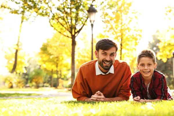 Šťastný otec a syn leží v parku na trávě. Podzimní procházka — Stock fotografie