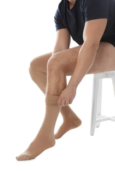 Άντρας που βάζει την κάλτσα συμπίεσης σε λευκό φόντο, κοντινό πλάνο — Φωτογραφία Αρχείου