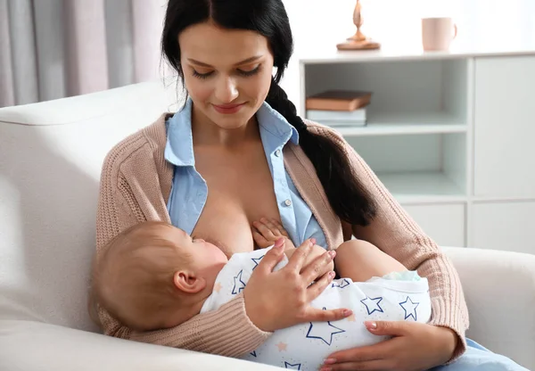 Žena kojit své dítě v křesle doma — Stock fotografie