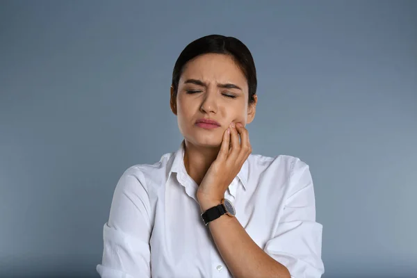 Vrouw die lijdt aan kiespijn op grijze achtergrond — Stockfoto