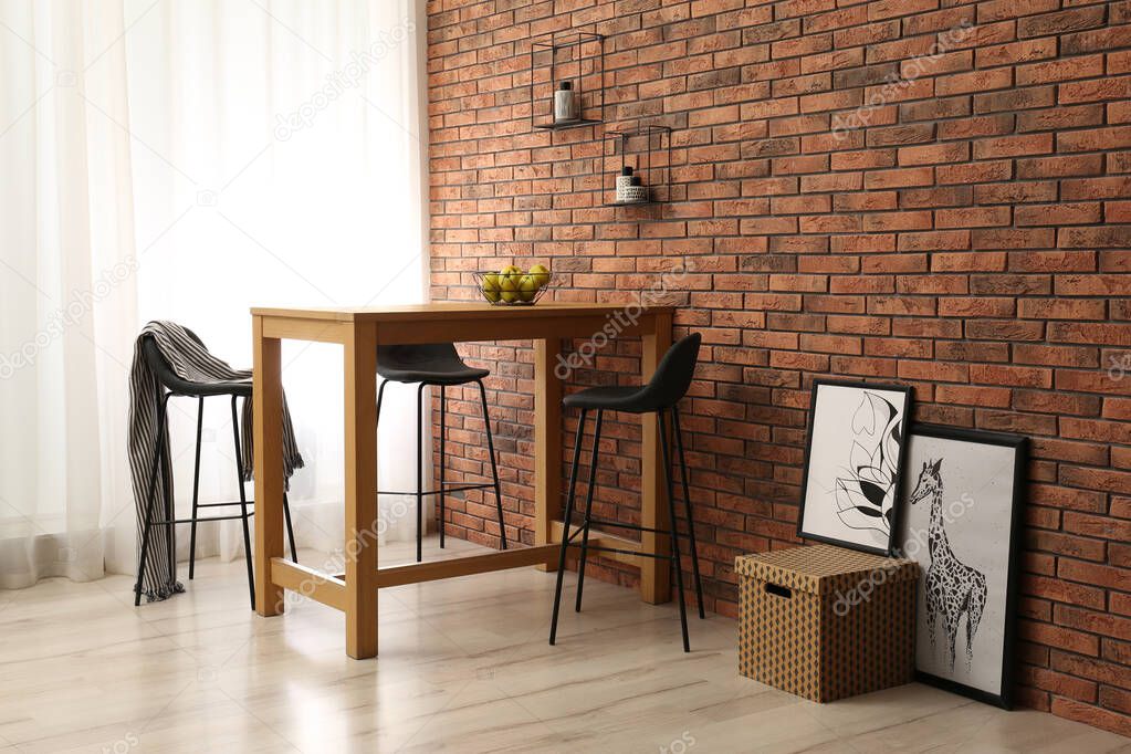 Elegant room interior with wooden table near brick wall