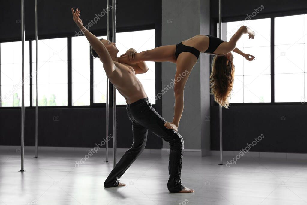Young couple dancing in studio with poles