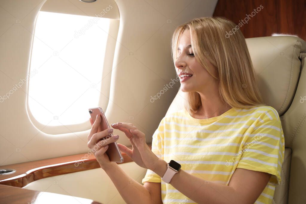 Young woman with phone travelling by plane. Comfortable flight