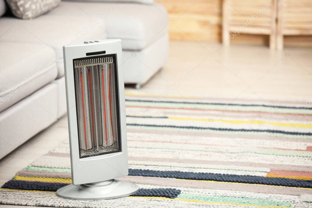 Modern electric infrared heater on floor at home. Space for text
